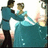 Two figures in formal attire dance; one wears a teal gown with flowing skirt, the other dark pants and matching teal jacket.