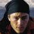 Static 50x50 pixel icon showing a person with dark hair and light skin in close-up, wearing a dark cap or head covering against a blurred background.