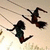 Two figures on a swing set; one figure swings forward while the other remains stationary.