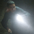 A pixelated figure in dark clothing holds a large glowing object against a dark background.