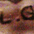 Pixelated static image with indistinct shapes in brown, purple, and beige tones, lacking clear subjects or text.