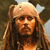 Pixelated image of a person with long brown hair wearing a light-colored head covering, dark clothing, and a neutral expression against a blurred background.