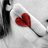 A static pixelated image shows a red heart-shaped object on a white curved surface against a gray background with dark vertical elements.