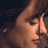 Pixelated close-up of a person's face with brown hair and closed eyes against dark background, rendered in low-resolution 256x256 pixels.