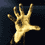 Pixelated golden hand with five fingers extended against dark background, rendered in low-resolution style.