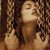 Static pixelated image of a person with closed eyes and raised hands against dark background, rendered in warm brown tones.