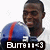 Pixelated image of a person wearing blue and red sports jersey with white accents, standing against light background.