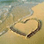 A heart drawn in wet sand on a beach, with gentle waves lapping at the shore and three distinct states of wave interaction visible.