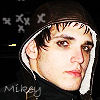 Pixelated close-up of a person with dark hair and a hooded garment, set against a dark background with faint star-like shapes and partial text.
