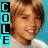 A pixelated image of a person with light brown hair and fair skin, wearing a white shirt against a blue background with vertical text reading "COOL" on both sides.