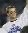 Static image of a person in a white sports jersey with blue and red details, raising one arm, against a blurred background.