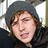 Pixelated close-up of a person with dark hair wearing a gray beanie and black clothing against a light background.