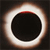 A circular black shape with a bright white ring and brownish outer glow on a dark background.