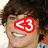 A pixelated image of a person with dark curly hair, wearing an orange and white shirt, smiling broadly.
