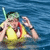 Pixelated figure in yellow life vest with red straps, holding a green snorkel, positioned against blue water background.