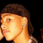 Pixelated close-up of a person's face with brown hair, light skin tone, and visible ear against dark background.