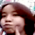A pixelated image of a person with long brown hair, closed eyes, and a finger near their mouth, with text above the head.