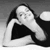 Black-and-white pixelated static icon of a person with long dark hair lying down, wearing a black top and white sleeves, against a gradient gray background.