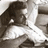Pixelated grayscale image of a figure with dark hair and light clothing, partially obscured by high compression artifacts.