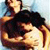 Two figures in a close embrace, one with dark hair and a dark sleeveless top, the other with light hair and a light sleeveless top, against a blurred background.