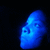 Blue pixelated face with closed eyes and a small mouth on black background.