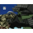 Animated sequence showing a large dark mechanical creature with green accents and a smaller brown creature interacting against a blue sky background.