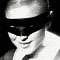 Black-and-white animated sequence of a person wearing a dark mask, showing subtle facial expression changes across frames.