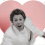 Pixelated figure with dark curly hair and white wings against pink heart background, mouth open in expression.