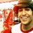 A pixelated image shows a person in a red jacket and brown cap holding a phone to their ear, with a bright red background displaying yellow text.