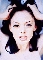 Static pixelated image of a person with dark hair wearing a white top, hands raised near head against light blue background.