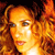 Pixelated close-up of a person with light brown hair and blue eyes, set against a dark background with orange and red tones.