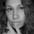 Black-and-white image of a person with long curly hair resting their chin on one hand, displayed in three overlapping