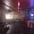 Pixelated image showing a dimly lit interior with a bright light source on the left and a blue light on the right, featuring indistinct shapes and muted colors.
