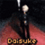 A pixelated character with a light-colored head and dark body stands on a red surface under a black background, with the text 'Daisuke' below.