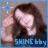 Pixelated image of a person with long brown hair and light skin, wearing dark clothing against a blue background.