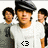 A person in a white shirt and dark cap stands centered with two figures behind, the lower-left icon shows '<3' while the upper-right shows '...' on their chest.