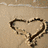 A heart drawn in sand, two people embracing, and text reading 'Phil + Katie <33' on a black-and-white background.
