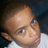 Pixelated close-up of a person's face with light skin tone, dark hair, and visible ear against dark background.