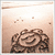 A pixelated image of a brown and beige spiral-shaped object against a light gradient background with scattered small squares.