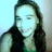 Pixelated static image of a person with long dark hair wearing a dark sleeveless top against a light blue and gray background.