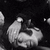 Black-and-white pixelated image with two distinct sections: a top section showing a person's face and hands, and a bottom section depicting multiple people in an embrace.