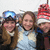 Three people pose together in a pixelated image; the left person wears a blue helmet, the middle person has long brown hair and light clothing, and the right person wears a red-and-white striped hat.