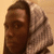 A person wearing a light-colored hooded garment with dark trim, viewed from the side against a neutral background.