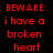 Red pixelated text on black background reads 'BEWARE: i have a broken heart ..see what you did to me?' next to grayscale image of person with arms crossed.