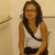 A pixelated image of a person with long dark hair wearing a white sleeveless top and black bottoms, standing against a light beige background.