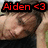 A pixelated image of a person with brown hair holding their head, overlaid with red text reading "Aiden <3" and multiple heart symbols.
