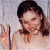 A pixelated image of a person with brown hair making a peace sign, next to green text reading 'Original Icons .com' on a dark background.