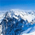 Pixelated blue and white image showing a stylized wave or cloud formation against a gradient sky background.