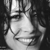 Black-and-white pixelated static icon showing a stylized human face with closed eyes and a slight smile, rendered in grayscale tones on a dark background.
