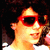 A person with dark curly hair and red sunglasses appears in a of four , with the bottom-right empty